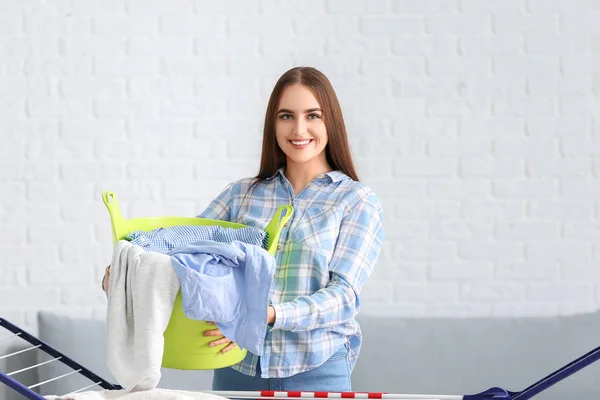 Beautiful young woman with clean laundry at home — Stock Photo, Image