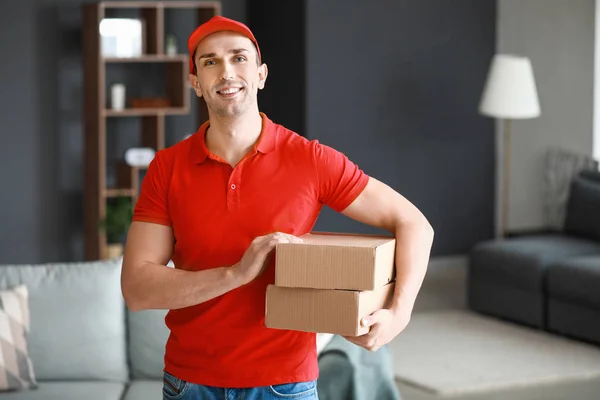Handsome delivery man with boxes indoors — Stock Photo, Image