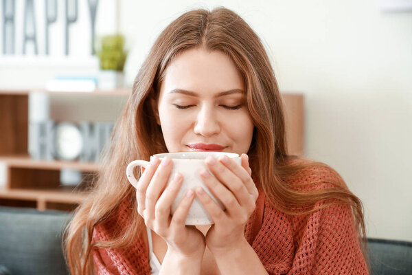 Happy woman with cup of tea resting at home