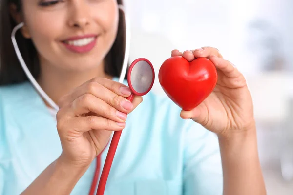 Cardiologista feminina com coração vermelho na clínica moderna, close-up — Fotografia de Stock