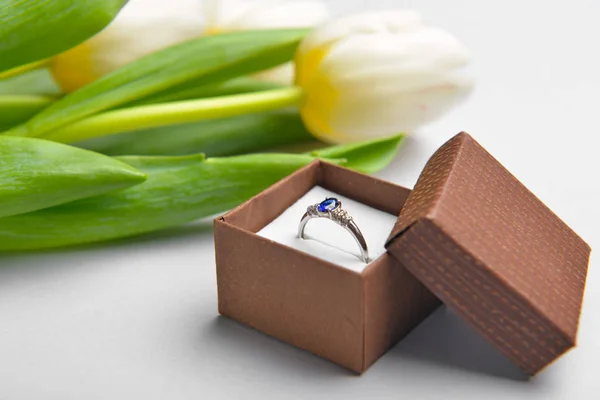 Prachtige ring en bloemen op lichte achtergrond. Internationale Vrouwendag viering — Stockfoto