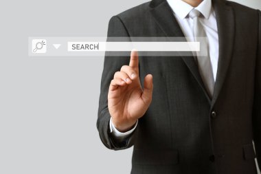 Gri arkaplana karşı web arama motoru kullanan işadamı, yakın plan