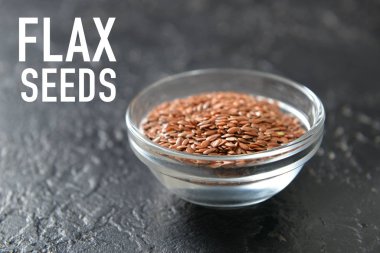Koyu arkaplanda keten tohumları olan bir kase