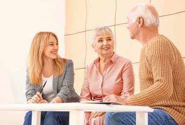 Bayan emlakçı içeride yaşlı bir çiftle çalışıyor.