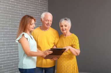 Bayan emlakçı içeride yaşlı bir çiftle çalışıyor.