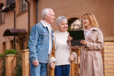 Binanın yakınında müşterileri olan kadın emlakçı.