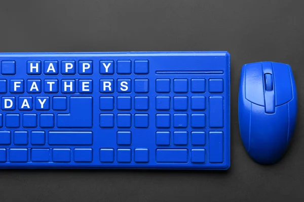 Blue computer mouse and keyboard with text HAPPY FATHER\'S DAY on dark background