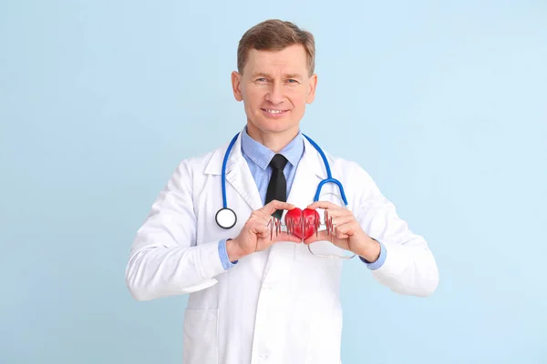 Muž kardiolog s červeným srdcem na barevném pozadí — Stock fotografie
