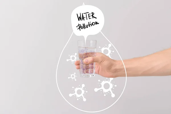 Male hand with glass of water and drawn drop with microbes on light background. Problem of pollution — Stock Photo, Image