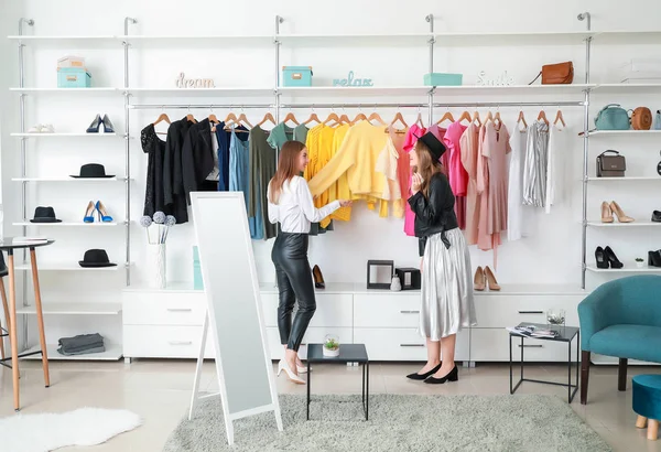 Vendedor ayudando a la joven a elegir la ropa en la tienda — Foto de Stock