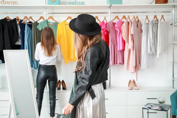 Красивая молодая женщина с одеждой возле зеркала в магазине — стоковое фото