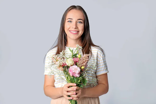 Portrait of happy woman with bouquet on grey background — Stock Photo, Image