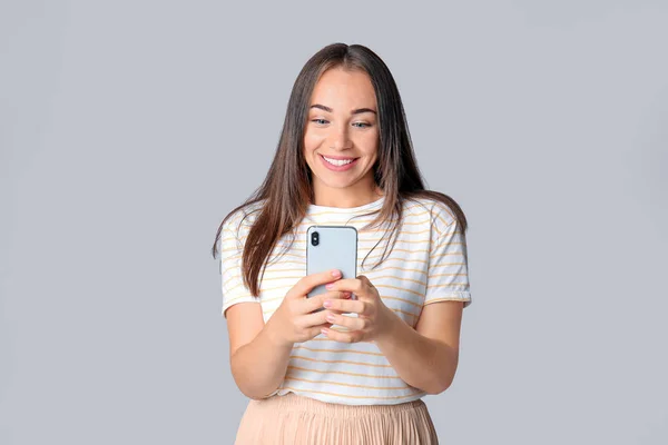 Retrato de mujer hermosa con teléfono móvil sobre fondo gris — Foto de Stock