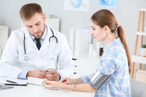 Médico do sexo masculino medindo a pressão arterial de paciente do sexo feminino na clínica — Fotografia de Stock