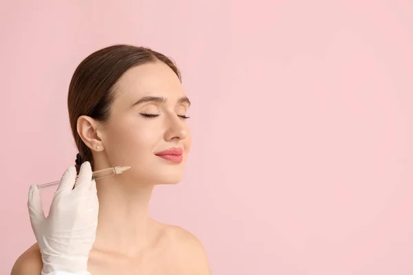 Young woman receiving filler injection against color background — Stock Photo, Image