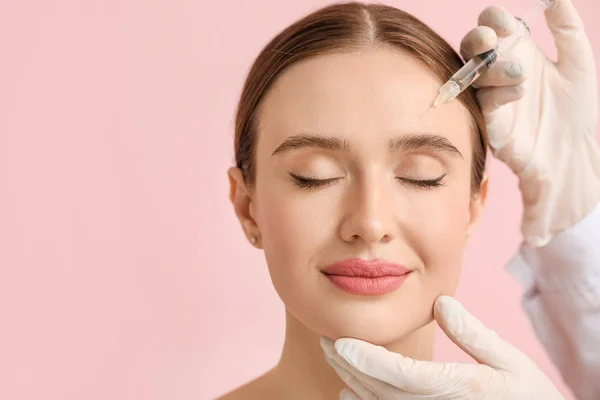 Jonge vrouw die vulmiddel injectie tegen kleur achtergrond — Stockfoto