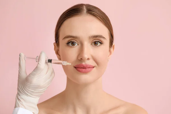 Young woman receiving filler injection against color background — Stock Photo, Image