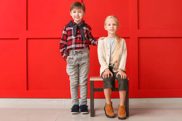 Bambini piccoli e carini in abiti autunnali vicino alla parete di colore — Foto Stock