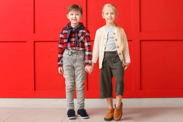 Bambini piccoli e carini in abiti autunnali vicino alla parete di colore — Foto Stock