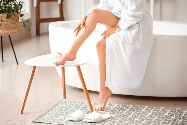 Belle jeune femme appliquant crème pour le corps dans la salle de bain — Photo