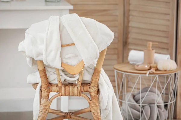 Soft clean bathrobe on wicker chair — Stock Photo, Image