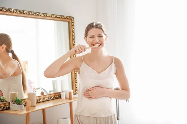 Giovane donna incinta lavarsi i denti in bagno — Foto Stock