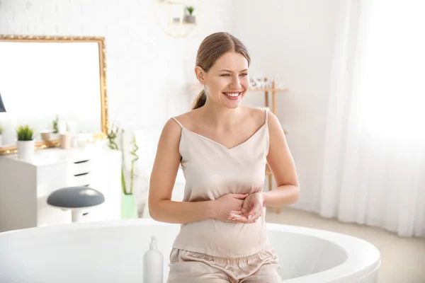 Mulher grávida bonita aplicando creme corporal no banheiro — Fotografia de Stock