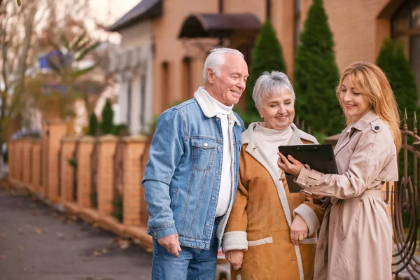 Binanın yakınında müşterileri olan kadın emlakçı.