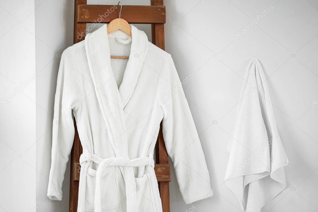 Soft clean bathrobe and towel in bathroom