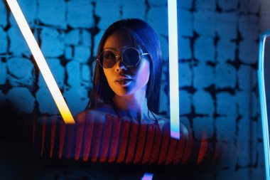 Koyu renkli arka planda neon lambaları olan güzel bir kadının tonlu portresi.