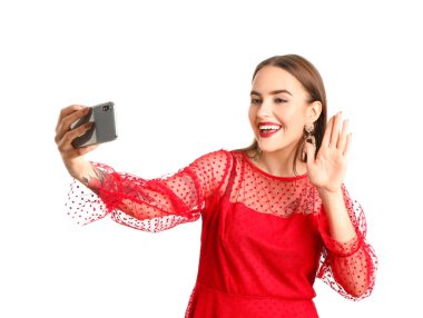 Güzel genç bir kadın beyaz arka planda selfie çekiyor.