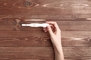 Ahşap arka planda gebelik testi ile kadın el
