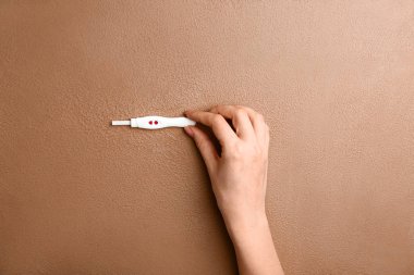 Renk arka plan üzerinde gebelik testi ile kadın el