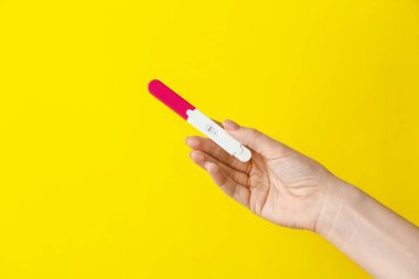 Renk arka plan üzerinde gebelik testi ile kadın el