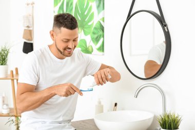 Evde dişlerini fırçalayan yakışıklı adam.