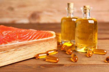 Yağlı balık ve tahta arka planda haplar.