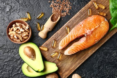 Yüksek omega 3 ve koyu arkaplanda balık yağı hapları olan sağlıklı ürünler.