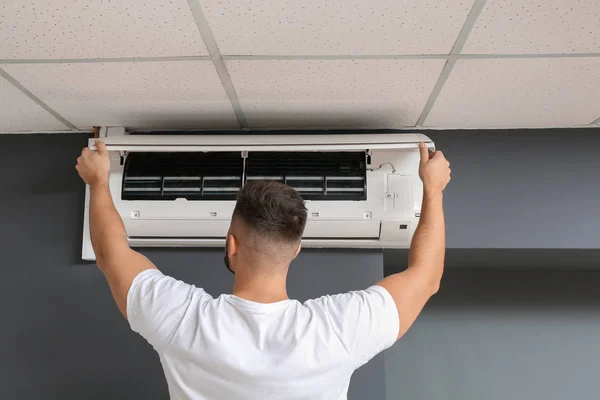 Male technician repairing air conditioner indoors — Stock Photo, Image