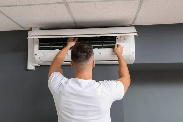 Técnico masculino reparando ar ar condicionado dentro de casa — Fotografia de Stock