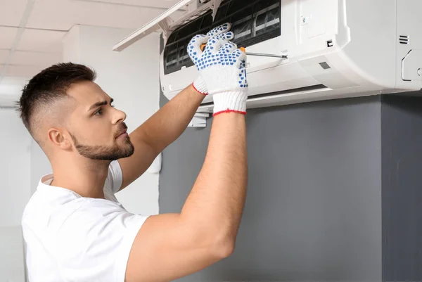 Técnico masculino reparando ar ar condicionado dentro de casa — Fotografia de Stock