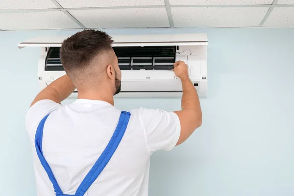 Técnico masculino reparando ar ar condicionado dentro de casa — Fotografia de Stock