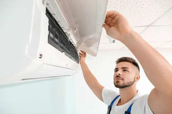 Técnico masculino reparando aire acondicionado en interiores —  Fotos de Stock