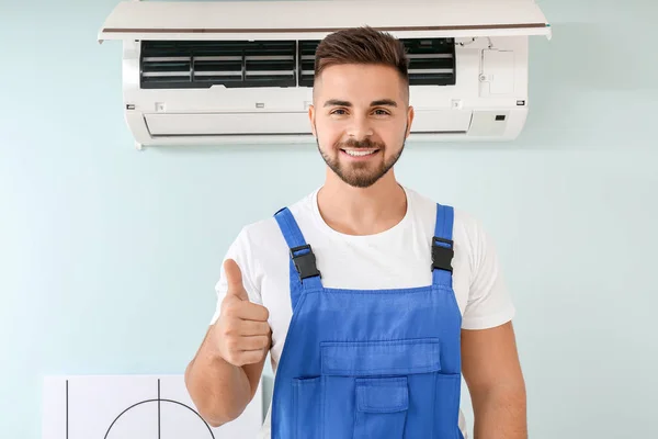 Técnico do sexo masculino mostrando polegar para cima após a reparação de ar condicionado — Fotografia de Stock