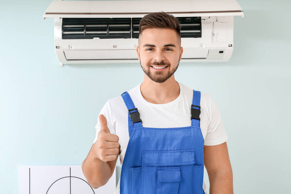 Male technician showing thumb-up after repairing air conditioner