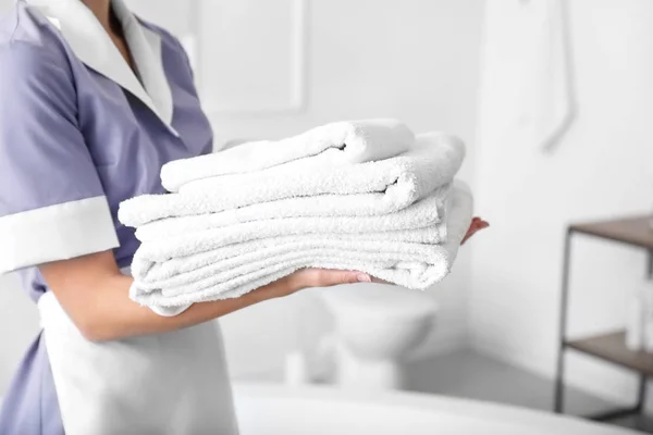 Hermosa camarera con toallas limpias en el baño del hotel — Foto de Stock