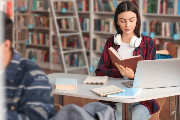 Studentin liest Buch während der Prüfungsvorbereitung in der Bibliothek — Stockfoto