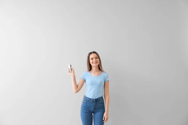 Mladá žena s klimatizací dálkové ovládání na bílém pozadí — Stock fotografie