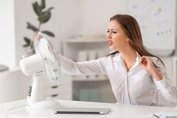 Indignante mujer que sufre de calor cerca de ventilador eléctrico en la oficina —  Fotos de Stock