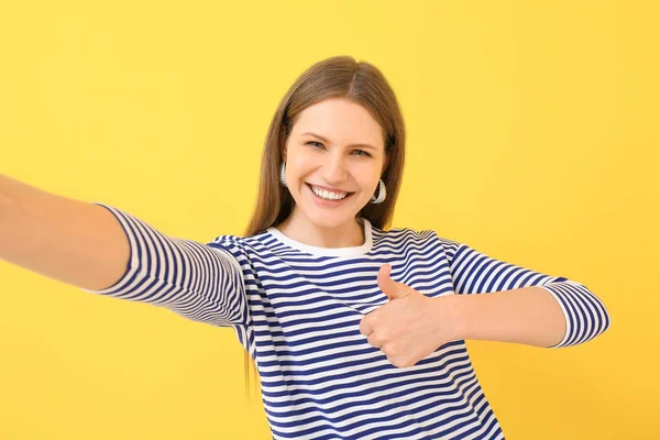 Schöne junge Frau macht Selfie auf farbigem Hintergrund — Stockfoto