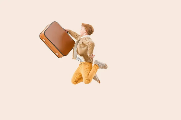 Skok malý chlapec s kufrem na světlém pozadí — Stock fotografie